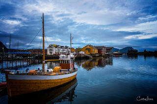 A classic wood ship sits in Svolvaer harbour at blue hour.