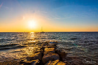 The sun dips into the sky at Menemsha beach in Martha's Vineyard, with vibrant blues and oranges
