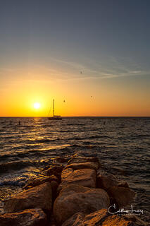 The sun dips into the sky at Menemsha beach in Martha's Vineyard, with vibrant blues and oranges