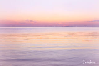 Vibrant colors pre-sunrise caused when the sunlight interacts with the earth's atmosphere results in a serene image of the the sky reflecting on the ocean