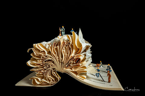 Fine art photo of an abstract folded book, featuring miniture figures forming geometric patterns , created by Toronto based photographer, Edith Levy
