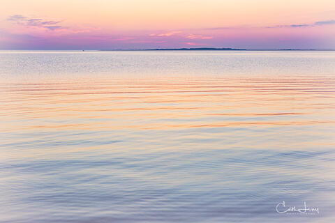 Vibrant colors pre-sunrise caused when the sunlight interacts with the earth's atmosphere results in a serene image of the the sky reflecting on the ocean