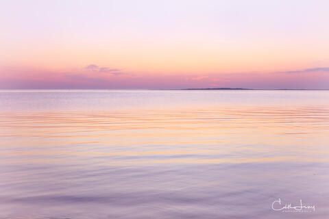 Vibrant colors pre-sunrise caused when the sunlight interacts with the earth's atmosphere results in a serene image of the the sky reflecting on the ocean