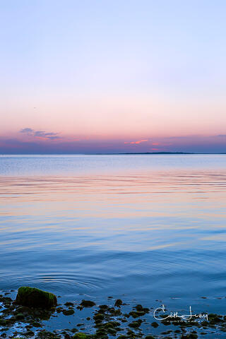 Vibrant colors pre-sunrise caused when the sunlight interacts with the earth's atmosphere results in a serene image of the the sky reflecting on the ocean